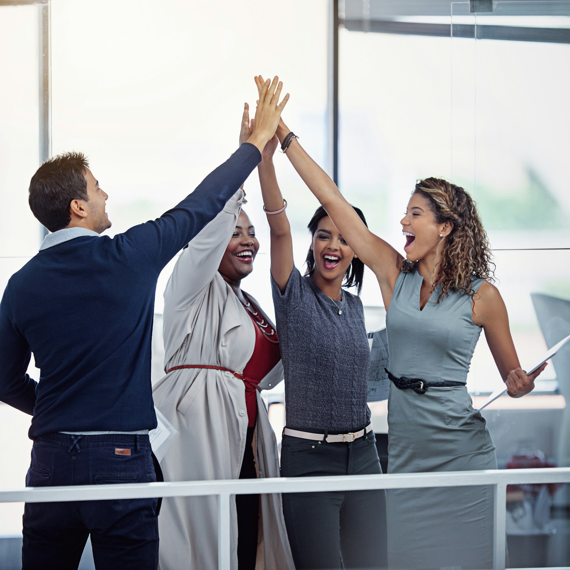 Succeeding as a team. Shot of a group of colleagues high fiving together in an office.